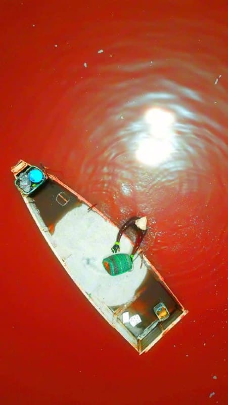 Vue aérienne d'une pirogue sur les eaux roses du Lac Retba